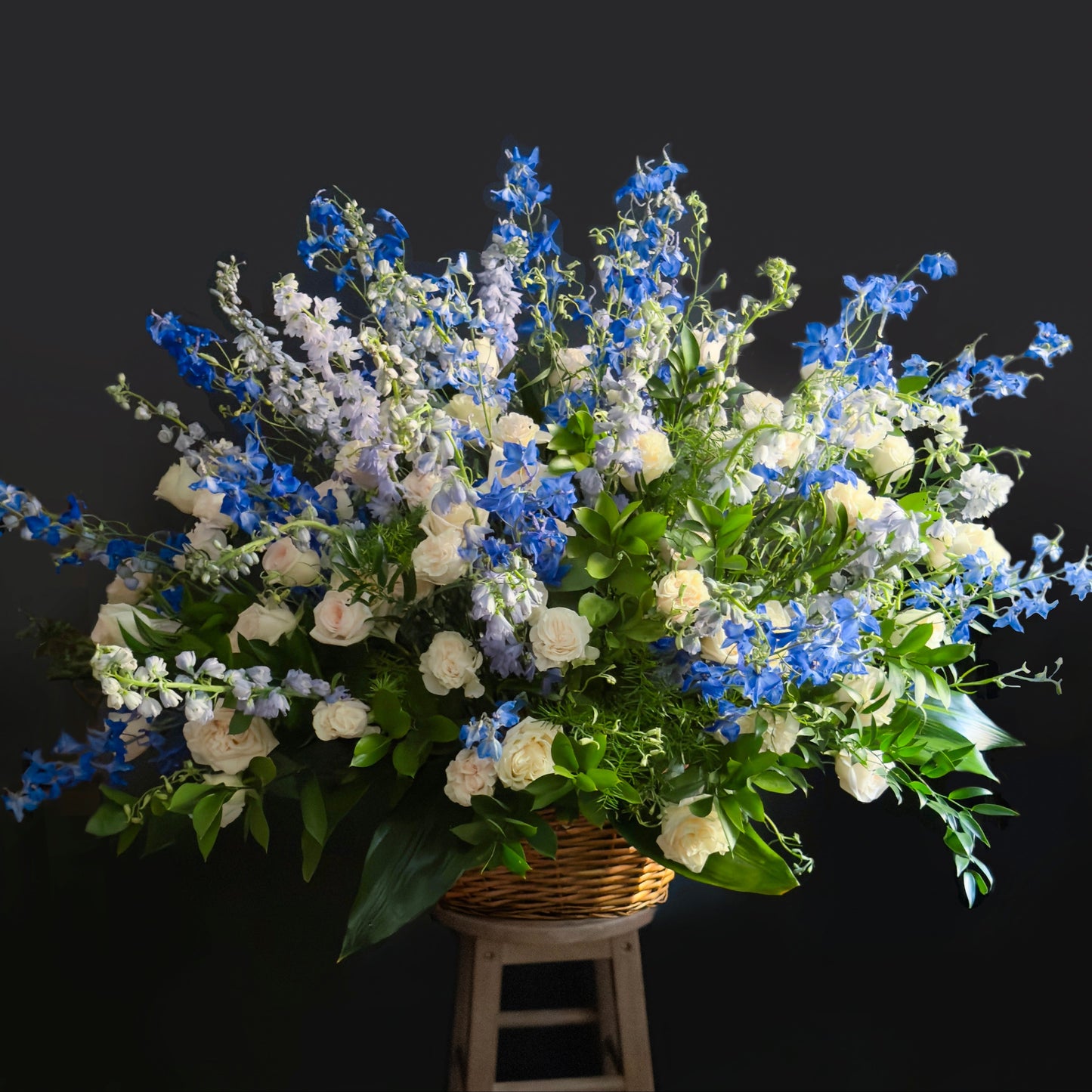 Bouquet of blue and white flowers in a woven basket on a black background