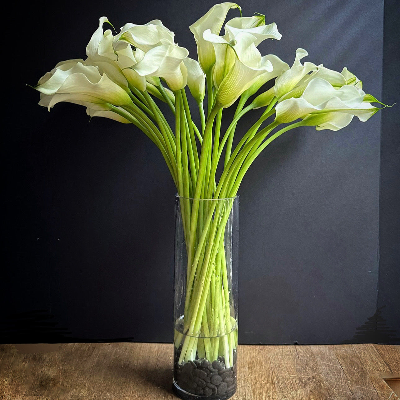 Clear vase with white flowers on a wooden surface against a dark background
